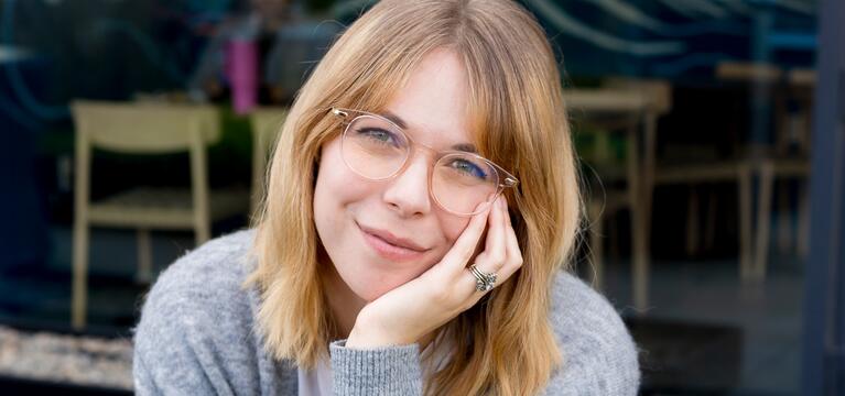 Photo of a woman with light chin length hair and a gray sweater with her chin resting on her hand