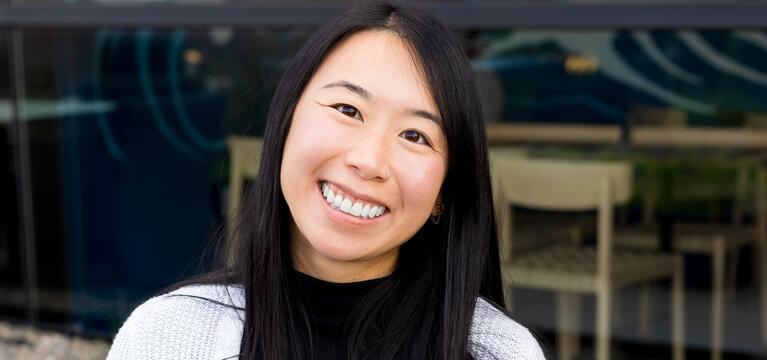 Photo of a woman with long dark hair a black shirt and a white cardigan