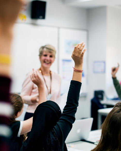 Students raising hands in classroom