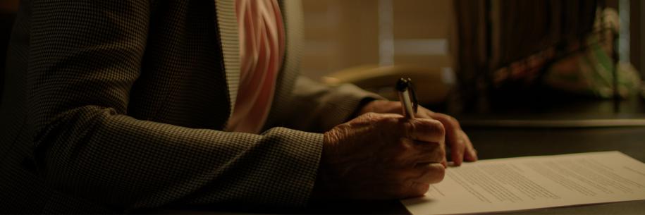Photo: woman writing with pen on desk