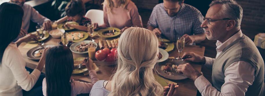 Photo of six family members sitting at a table eating and talking