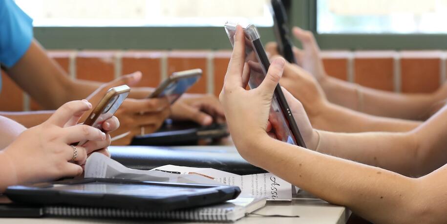 Four sets of hands holding cell phones at a table
