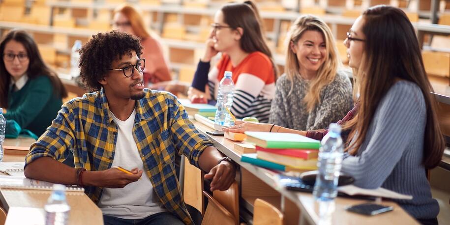 Photo of college students in a large lecture hall talking