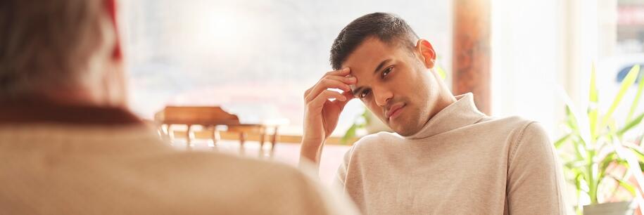Photo: man with short dark hair in a light sweater looking frustrated