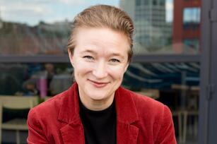Photo of a woman with short hair a black shirt and a maroon jacket