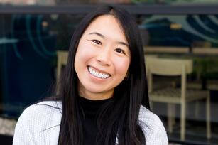 Photo of a woman with long dark hair a black shirt and a white cardigan