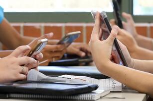 Four sets of hands holding cell phones at a table